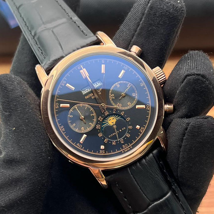 Reloj de lujo estilo Patek Philippe Geneva de 40mm, diseño automático con esfera azul multifunción, detalles en dorado y correa de piel negra.