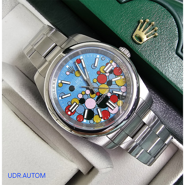 Reloj Rolex Oyster Perpetual Edición Limitada con esfera azul y diseño artístico colorido, brazalete Oyster de acero inoxidable, con ventana de fecha a las 3 y resistencia al agua de hasta 100 metros.