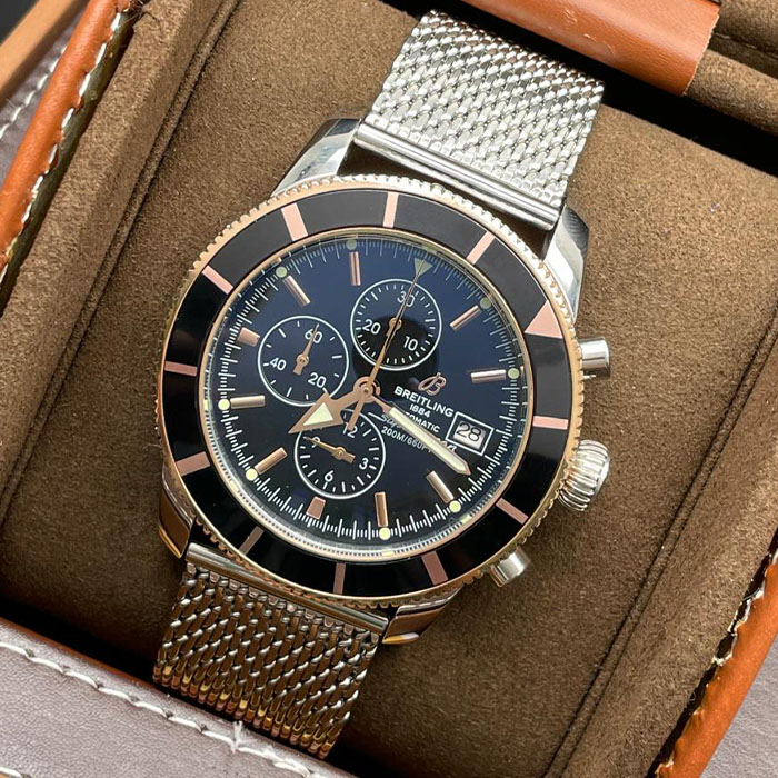 Reloj Breitling SuperOcean Automatic con carátula negra, detalles en oro rosado y brazalete de acero estilo malla.