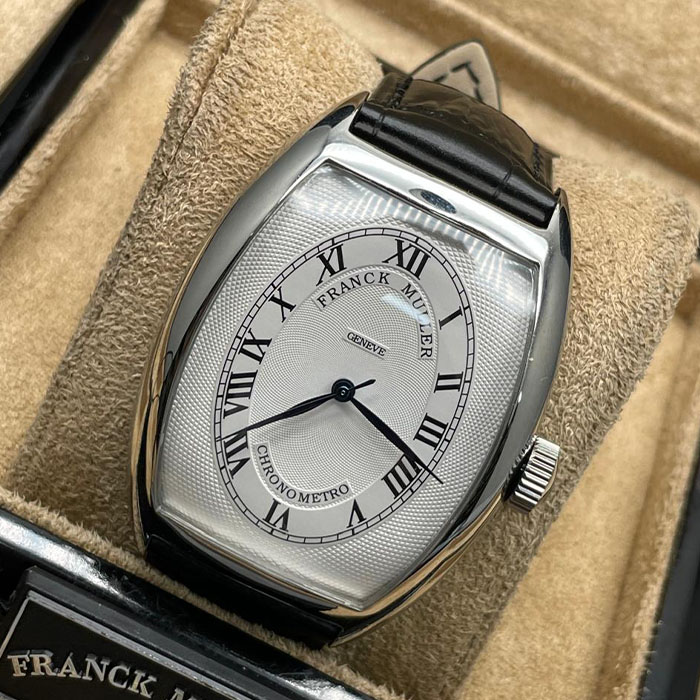 Franck Muller Geneve Chronometro, con esfera plateada y números romanos, caja de acero inoxidable y correa de cuero negro. Un reloj de lujo para ocasiones especiales.