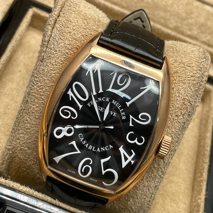 Franck Muller Geneve Casablanca con caja dorada, esfera negra y números blancos. Un reloj elegante y sofisticado con correa de cuero negro.