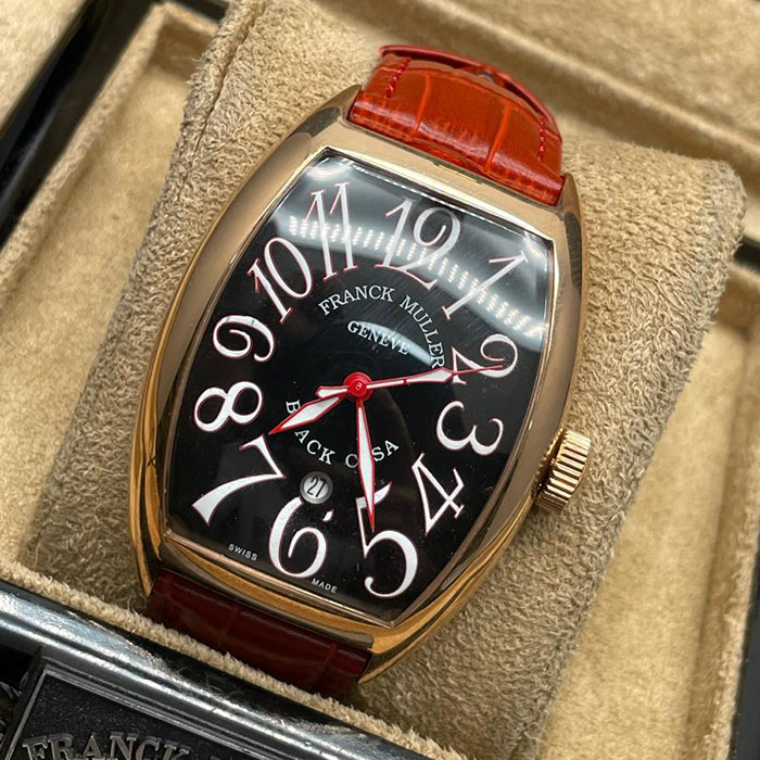 Franck Muller Geneve Black Casa, reloj de lujo con caja dorada, esfera negra con números blancos y rojos, y correa de cuero rojo, una pieza moderna y elegante.