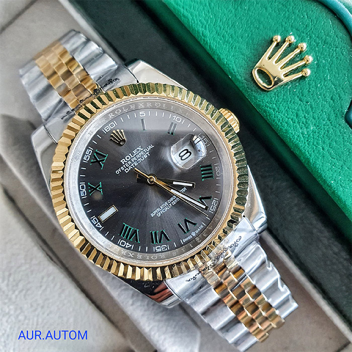 Reloj Rolex Oyster Perpetual Datejust con esfera gris, detalles en verde y bisel en oro amarillo, con brazalete de acero inoxidable, ideal para quienes buscan lujo y elegancia.