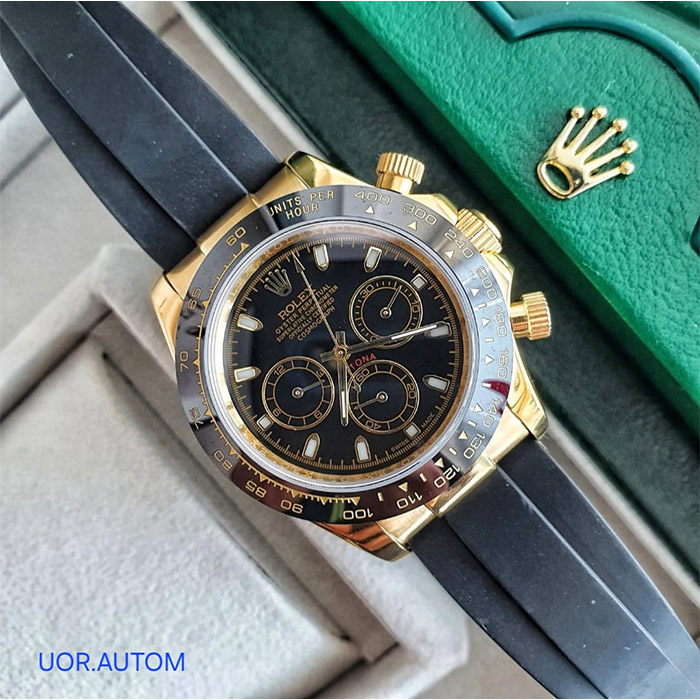 Reloj Rolex Oyster Perpetual Superlative Chronometer Daytona con esfera negra, cronógrafos dorados, caja de oro, bisel negro y correa de caucho negra.
